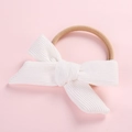 Detailed macro view of white corduroy bow headband with soft nude nylon band on pink background - White