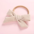 Détail du nœud en velours côtelé crème avec bandeau élastique rose sur fond pastel - Beige