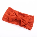 Close-up of soft nylon baby headband with a large bow in bright caramel color - Orange