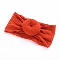 Close-up of caramel ribbed nylon baby headband with a 3D doughnut knot decoration - 10 Orange Red
