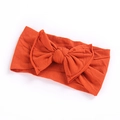 Detailed macro view of bright orange bow headband in soft high-elastic knitted cotton - Orange