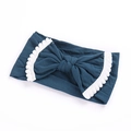 Detail of teal nylon baby headband featuring lace edges and white pom-pom bow trim - Dark Blue