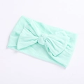 Close-up detail of soft mint green nylon baby headband with a large ribbed bow decoration - Emerald Green