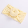 Detail of soft pale yellow nylon baby headband featuring a sweet donut-shaped knot design - Beige