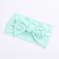 Macro detail of soft mint green nylon baby headband featuring a large bow on white surface - Emerald Green