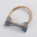 Gros plan d'un bandeau à nœud à carreaux bleu et beige avec bande élastique en nylon souple - Bleu à Carreaux