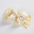 Close-up of baby headband featuring soft yellow nylon fabric and cream ribbed bow details - Beige