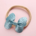 Détail d'un nœud à paillettes bleues sur un bandeau élastique rose pour bébé et enfant - Bleu lac