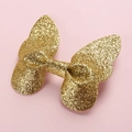 Close-up of golden glitter 3D butterfly hair clip on a soft pink background - Yellow