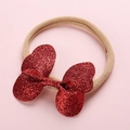 Dettaglio di un fiocco con paillettes rosse su una fascia in nylon morbido per neonati - Oro rosa