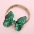 Détail d'un nœud pailleté vert sur un bandeau bébé en nylon souple sur fond rose clair - Vert Étincelant