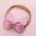 Détail du nœud rose pailleté sur un bandeau élastique en nylon pour bébé fille - Rose