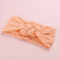 Détail d'un bandeau large pour bébé en rose pêche avec un design torsadé et tressé - Orange clair