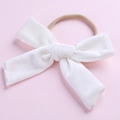 Détail d'un nœud en velours blanc avec bandeau en nylon élastique sur fond rose tendre - Blanc