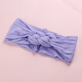 Gros plan d'un bandeau lilas pour bébé en nylon avec détail de nœud torsadé doux - Violet