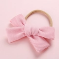 Gros plan d'un bandeau en velours rose avec un nœud et un élastique en nylon - Rose