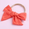 Détail d'un bandeau bébé en coton avec nœud et ruban en nylon élastique couleur pêche - Orange