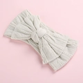 Close-up of a soft grey cable knit baby headband with a large decorative bow detail - Off-White