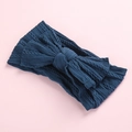 Detail view of navy blue cable knit infant headband with a large bow on pink backdrop - Ink Blue