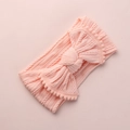 Vue détaillée du bandeau bébé en tricot torsadé avec grand nœud et bordure à pompons - Rose Clair