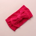 Détail d'un bandeau en tricot rose pour bébé avec nœud géant et bordure à pompons - Rose Vif