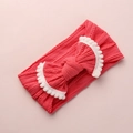 Détail du bandeau bébé rose corail avec grand nœud et bordure à pompons blancs doux - Rouge Pastèque avec Bordure Blanche