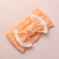 Détail du bandeau bébé en maille torsadée rose-orange avec nœud en dentelle pompon - Jaune Pêche avec Bordure Blanche