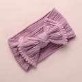 Détail du bandeau bébé tricoté rose poudré avec grand nœud à pompons décoratifs - Violet Taro
