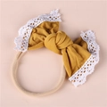 Close-up of mustard yellow bow headband with white lace trim and soft nylon band - Turmeric