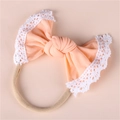 Detail of baby headband featuring peach bow with white lace trim on nude nylon band - Peach Yellow