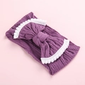 Détail d'un bandeau en tricot violet pour bébé avec grand nœud et bordure de pompons - Violet Clair avec Bordure Blanche