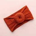 Detail of rust brown knitted baby headband with decorative donut knot and cable texture - Orange Red