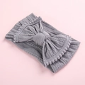 Détail du bandeau tricoté gris pour bébé avec nœud papillon et petits pompons - Gris