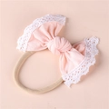 Close-up of soft pink baby bow headband featuring intricate white lace trim and elastic band - Dark Pink