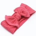 Détail d'un bandeau bébé en jacquard avec gros nœud et bordure pompon rose en rouge pastèque - Rouge pastèque