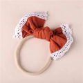 Detail of baby headband with burnt orange bow, white lace trim and nylon elastic band - Orange