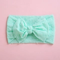 Detail of mint green nylon baby headband featuring soft pompom texture and bow knot - Verdant
