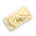 Close-up of soft yellow nylon baby headband featuring a large bow and 3D dot texture - Beige