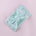 Detailed close-up of mint green baby headband featuring lace-edged bow and knit texture - Verdant