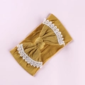Close-up of bright yellow baby headband with large lace-edged bow on pink background - Turmeric