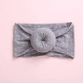 Detailed close-up of a grey elastic baby headband with white polka dots and donut knot - Gray
