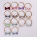 Flat lay of 14 colorful plaid bow baby headbands made of soft elastic nylon fabric - Random Color