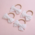 Détail de quatre bandeaux bébé en dentelle blanche avec nœuds et élastiques souples - Mélange Aléatoire