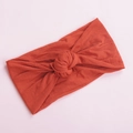 Detail of soft nylon baby headband with a decorative top knot in a warm brick red color - Orange Red (9)