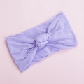 Detailed view of the soft lilac knotted nylon headband on a pale pink surface - Purple (25)