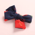 Texture dettagliata del fermaglio in velluto blu scuro con pois rossi e fiocco chic - Fiore Rosso