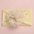 Detail of soft yellow nylon baby headband with a large layered organza flower on pink background - Beige