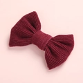 Detailed texture of a red corduroy bow hair clip with fine fabric ribbing and soft edges - Burgundy