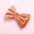 Detailed view of an orange velvet bow hair clip with fine texture and soft sheen - Light Orange