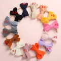 Flat lay showing 14 colorful knitted bow headbands for babies on pink background - Multicolor